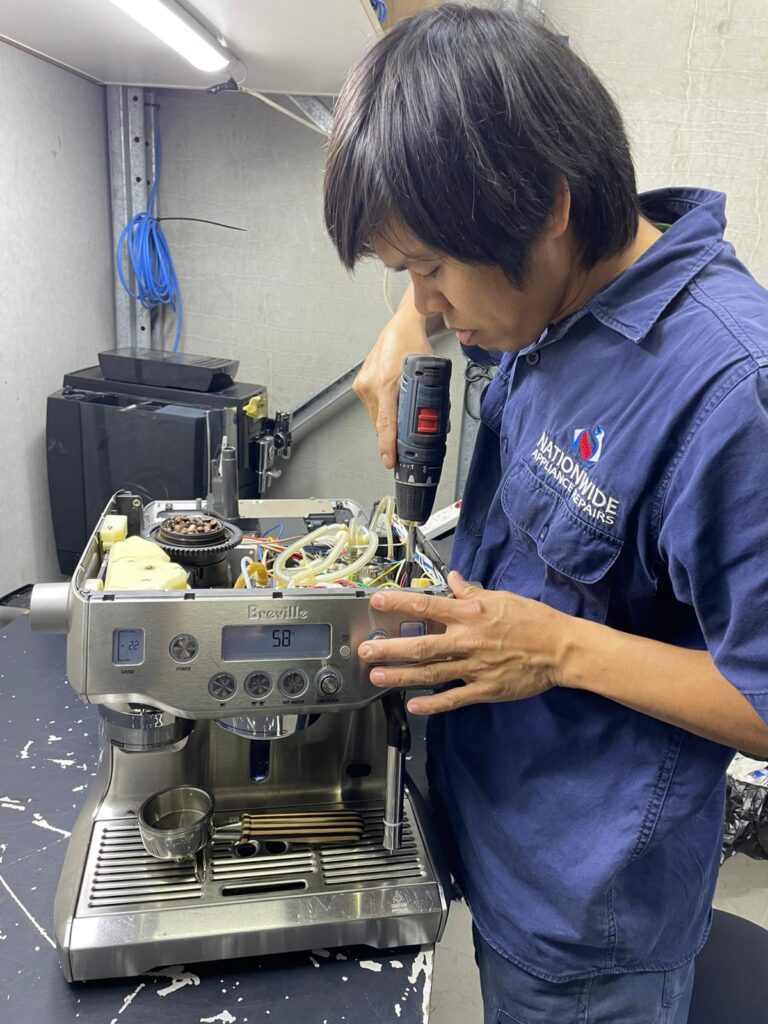 NAR technician using a power tool to open up a Breville coffee machine.