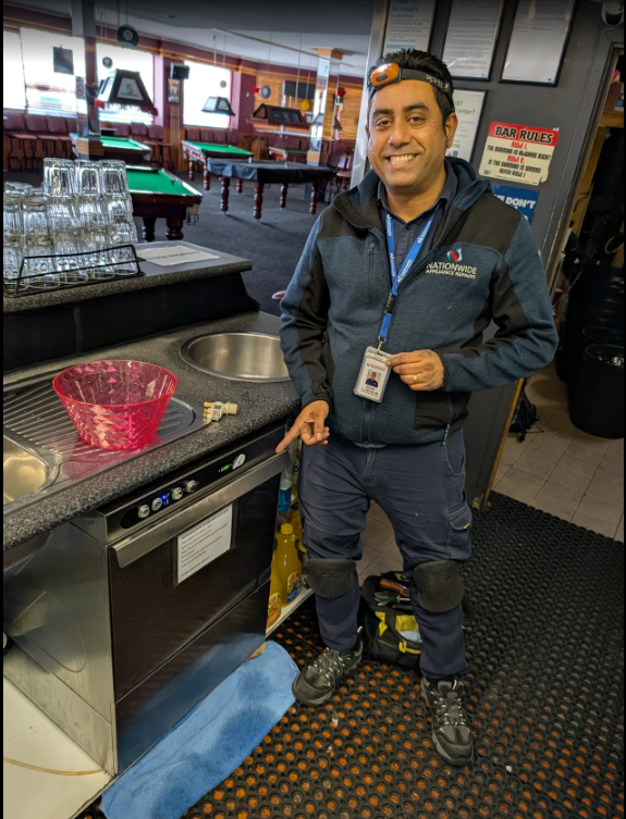 A NAR technician gesturing at a customer’s recently-repaired electric oven, with a red bowl on top.