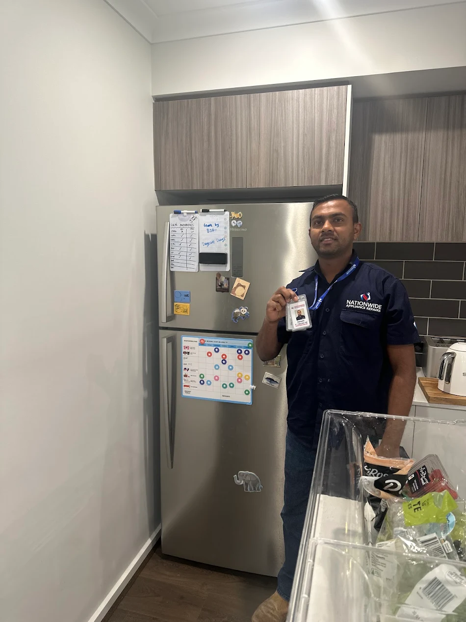 NAR technician holding ID badge in front of a repaired Hisense fridge in a customer’s residence. NAR technician holding ID badge in front of a repaired Hisense fridge in a customer’s residence.