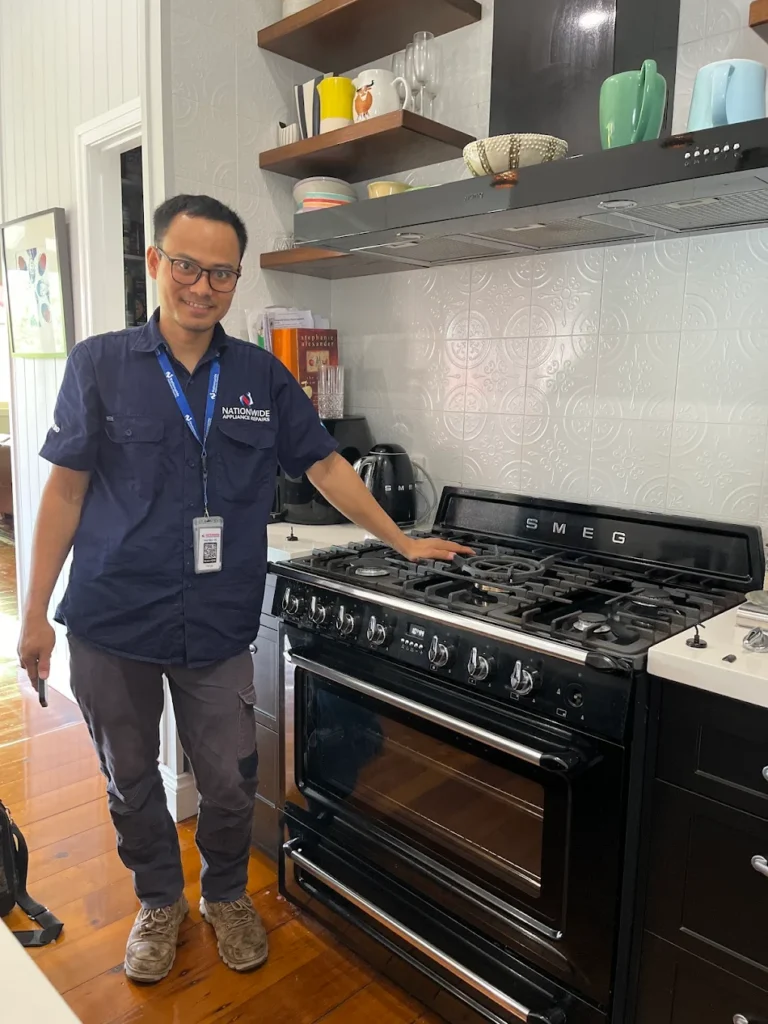 NAR technician standing and posing in front of a Smeg-branded gas oven in a customer’s residence.