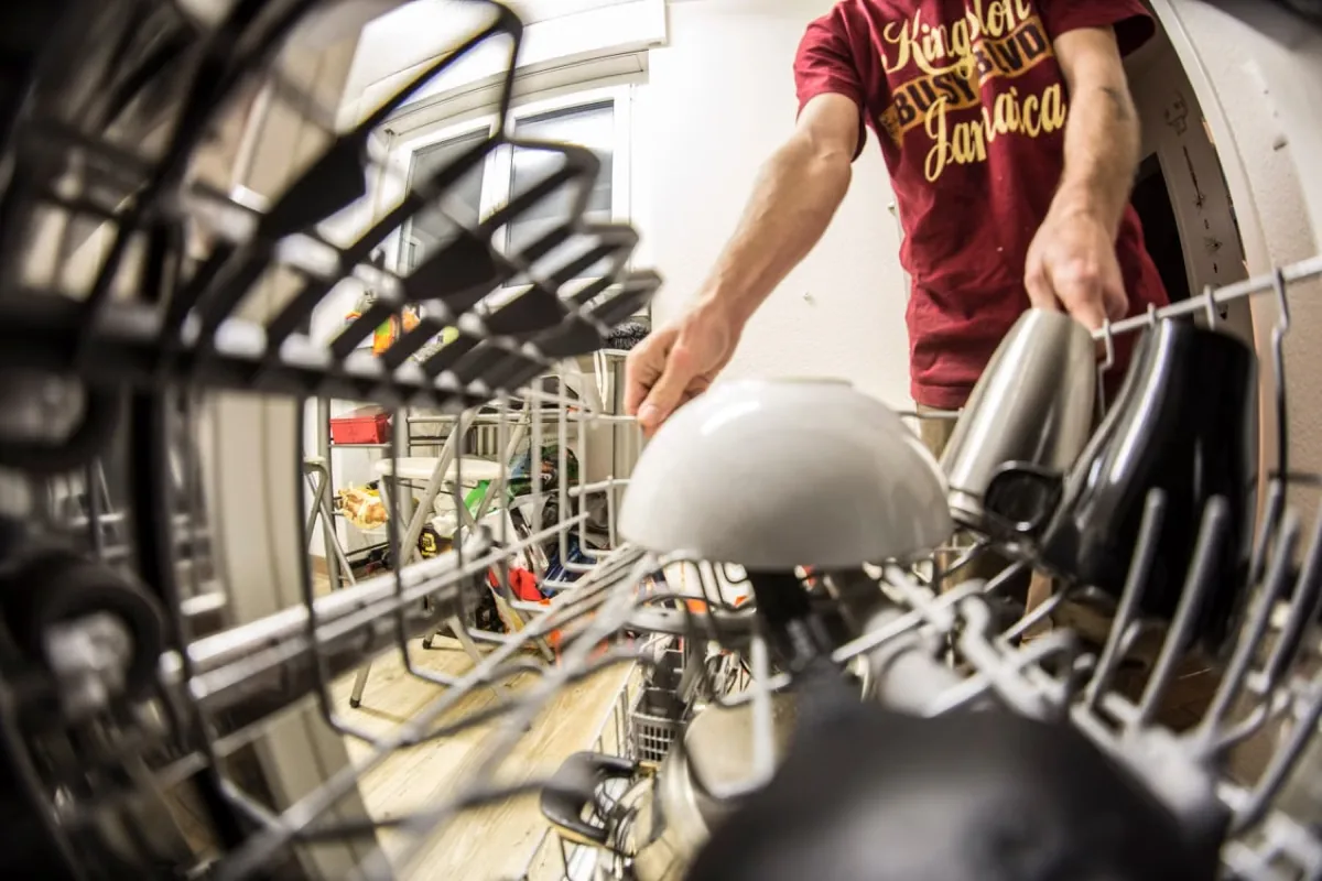 Fish eye photography of a man pulling the dishwasher rack.