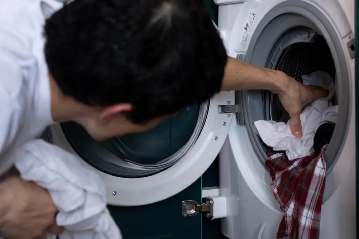 Man taking clothes out of a washing machine.
