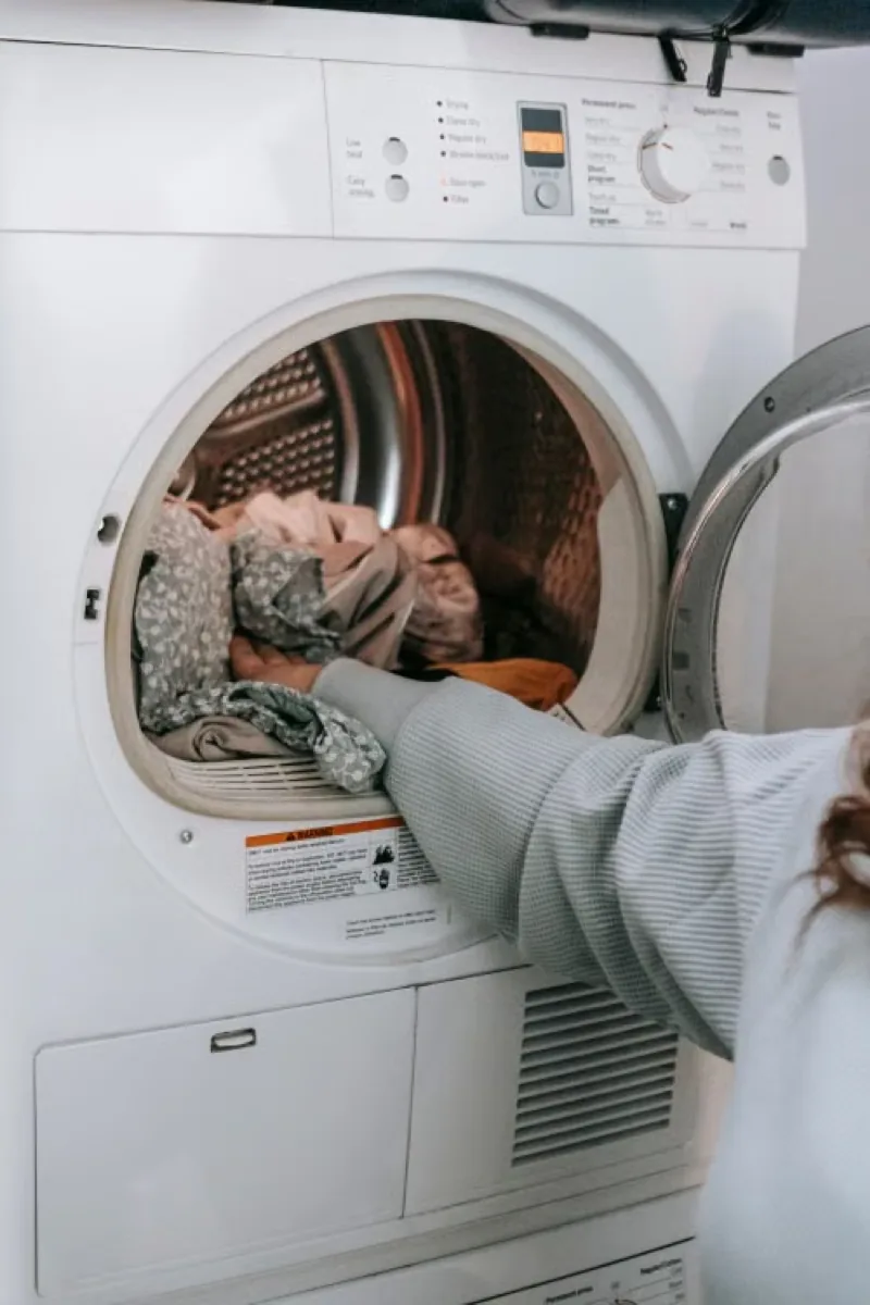 Woman putting clothes into a washing machine.