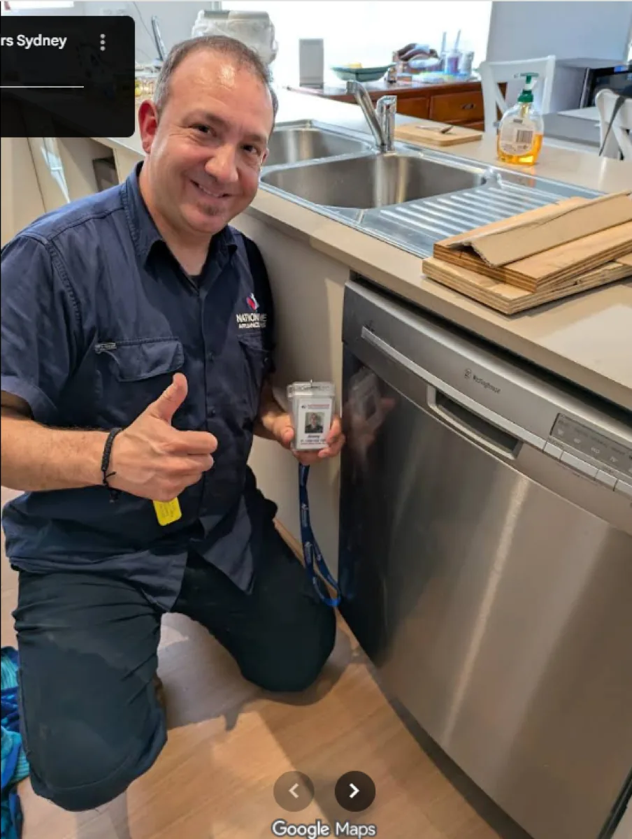 A NAR technician standing in front of a Westinghouse dishwasher in a client’s home, giving a thumb up.