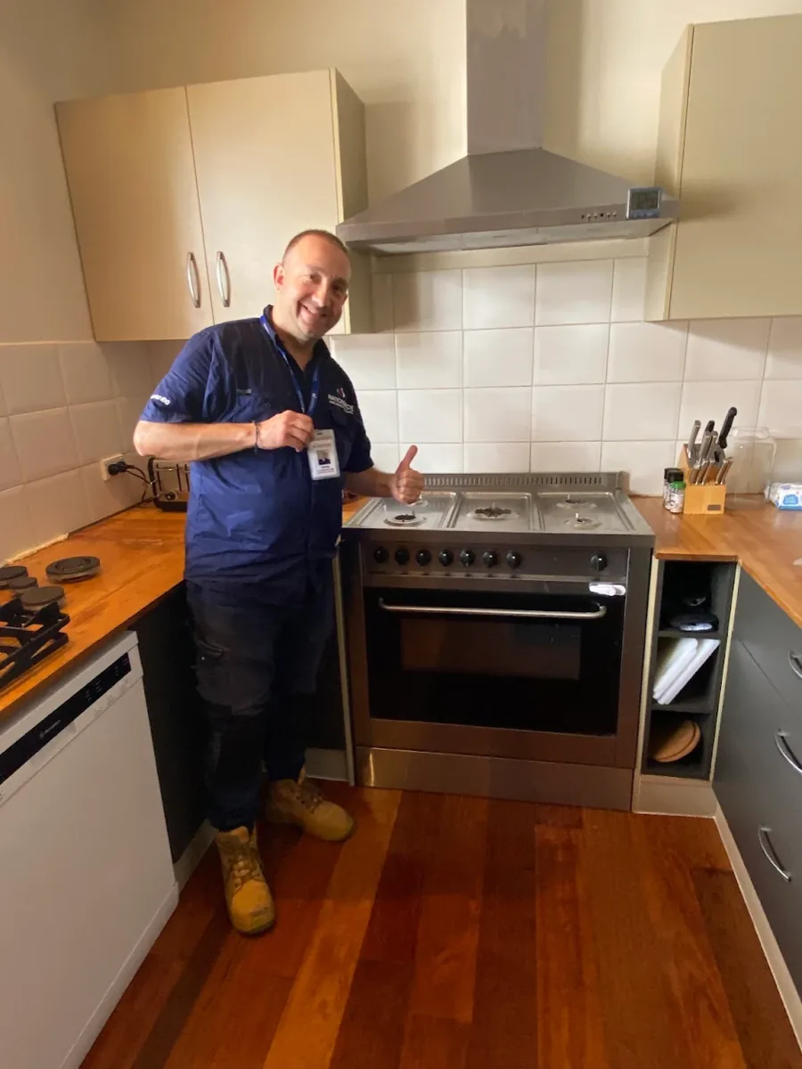 NAR technician giving a thumb up in front of a rangehood in a client’s home.