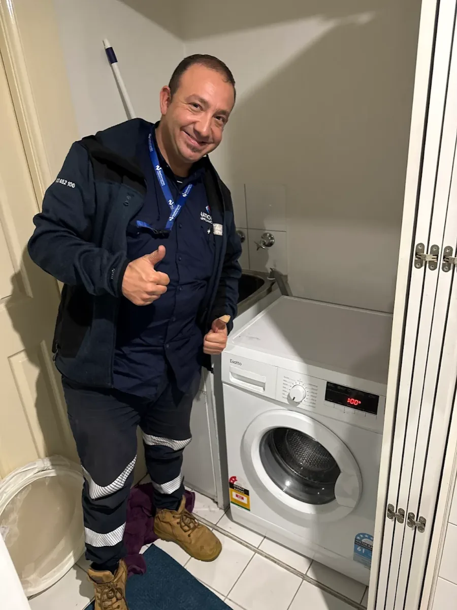 NAR technician giving a thumb up in front of a washing machine.