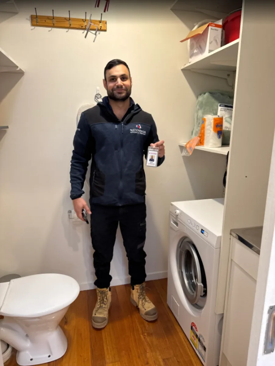 NAR technician showing his badge in front of a washing machine.