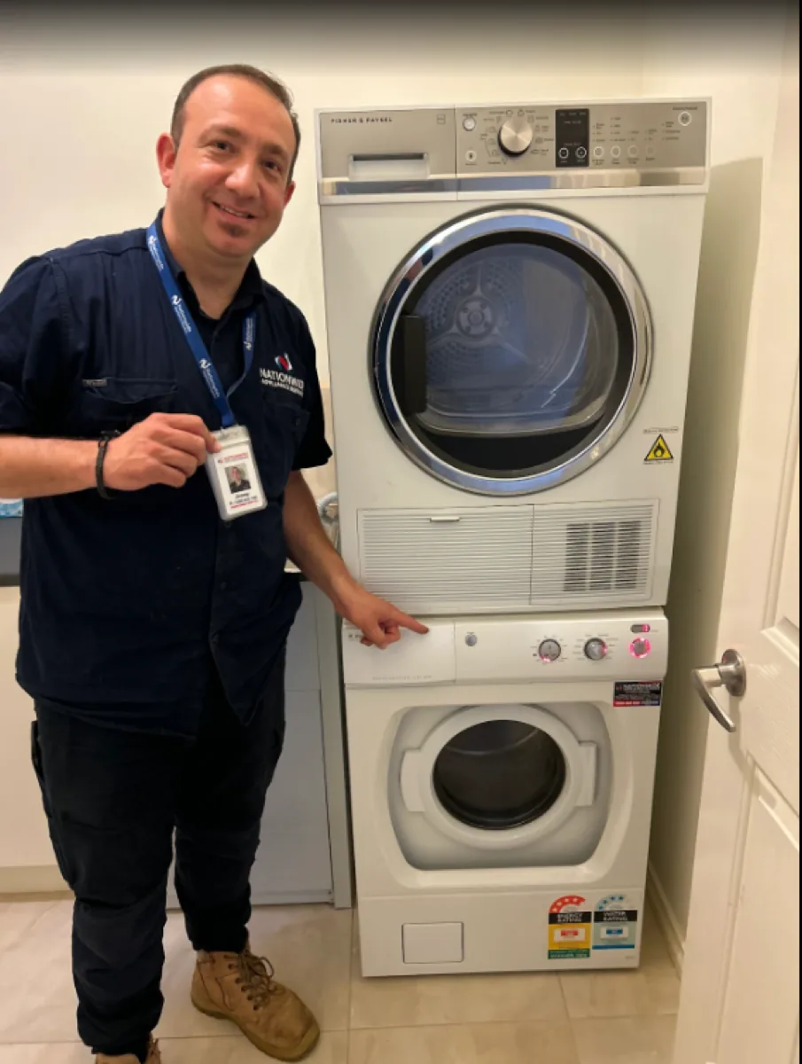NAR technician holding his badge in front of a client’s washing machine.