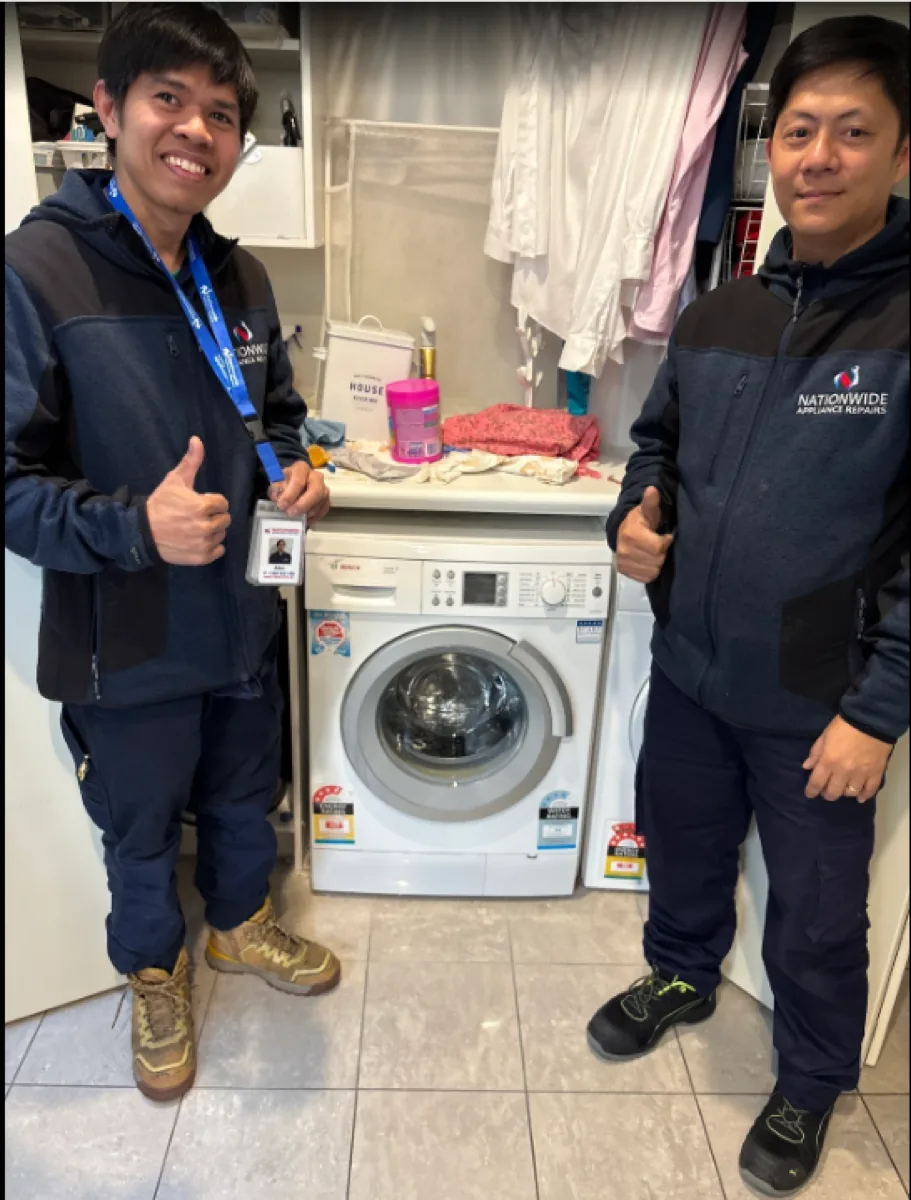 Two NAR technicians giving thumb ups in front of a front-loading washing machine.