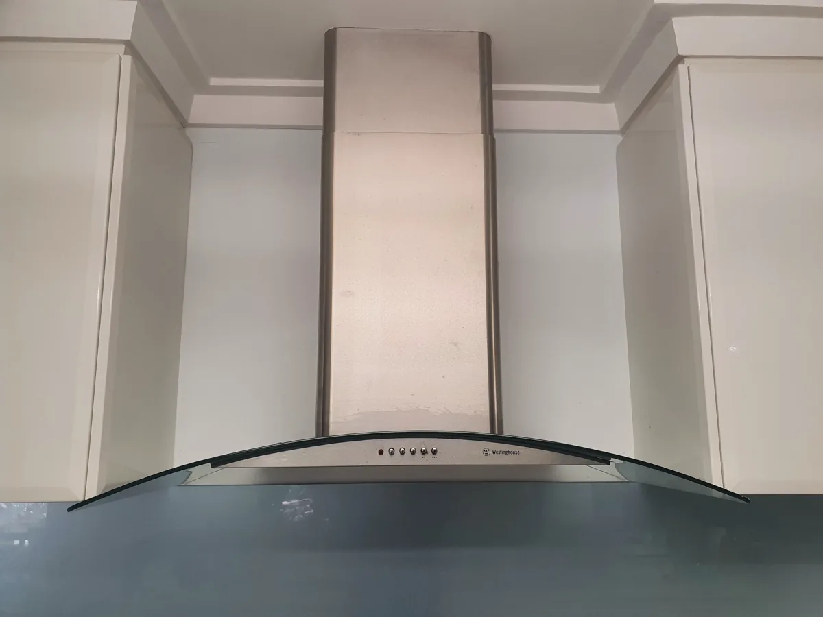 Westinghouse-branded rangehood with a glass canopy, connected to a metal exhaust that led to the ceiling in a NAR’s client’s home.